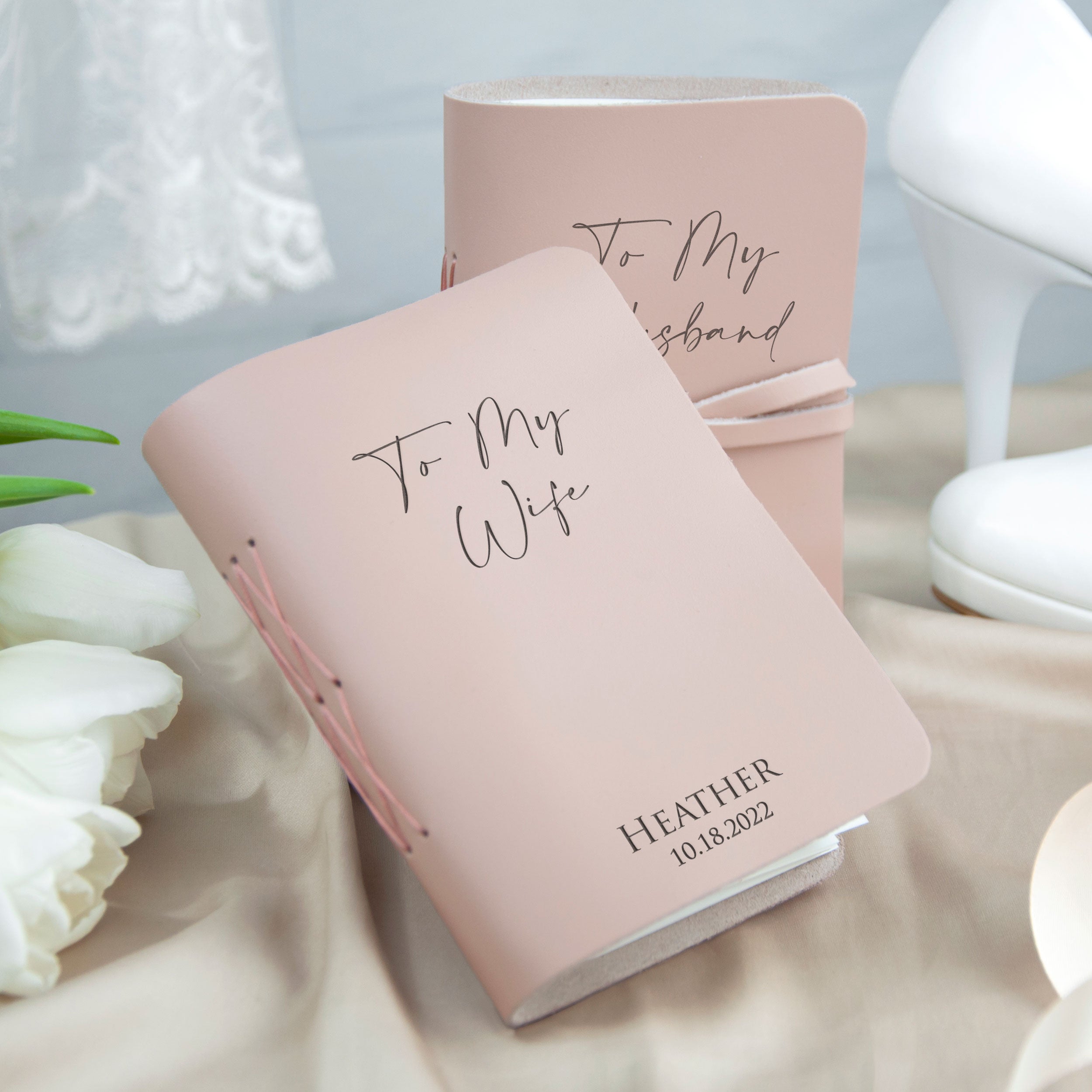 A pink engraved book titled "To My Wife" sits on a beige surface, with a white lace curtain visible in the background.