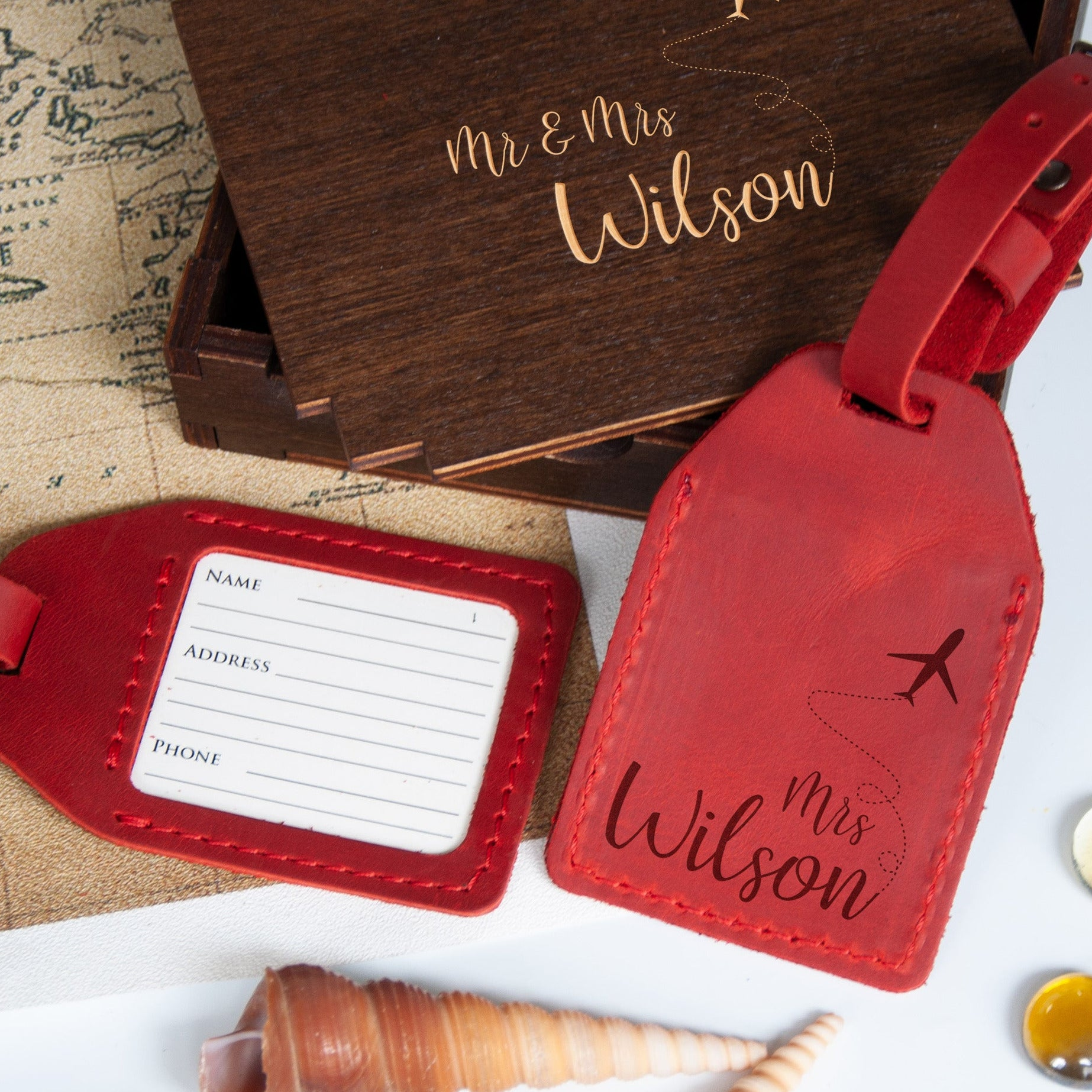 a wooden box with the name "Mr & Mrs Wilson" engraved on it, along with a red luggage tag that reads "Mrs Wilson" and a red tag with a plane image.