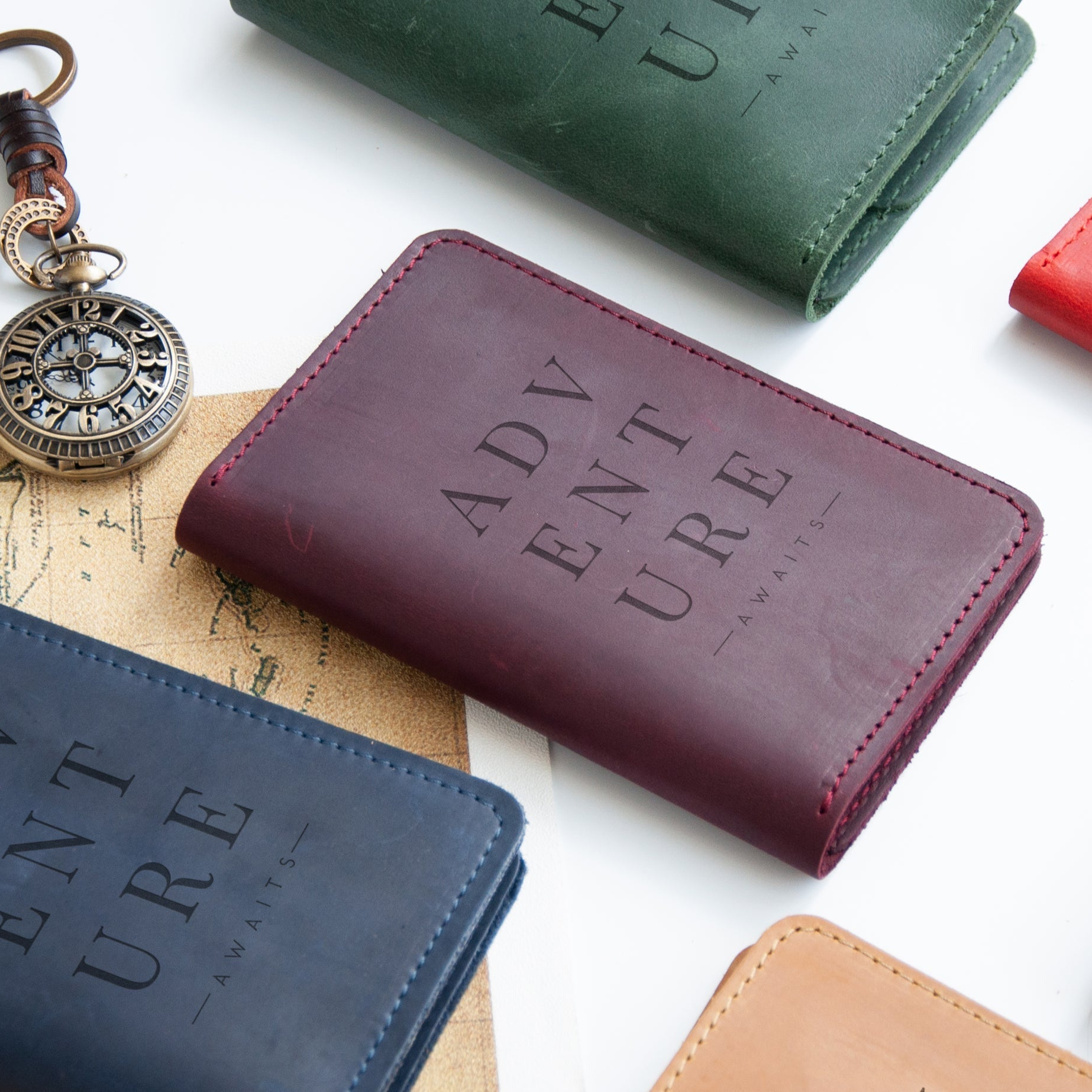 a collection of travel-related items, including a passport wallet, a pocket watch, and a map, all arranged on a white surface.