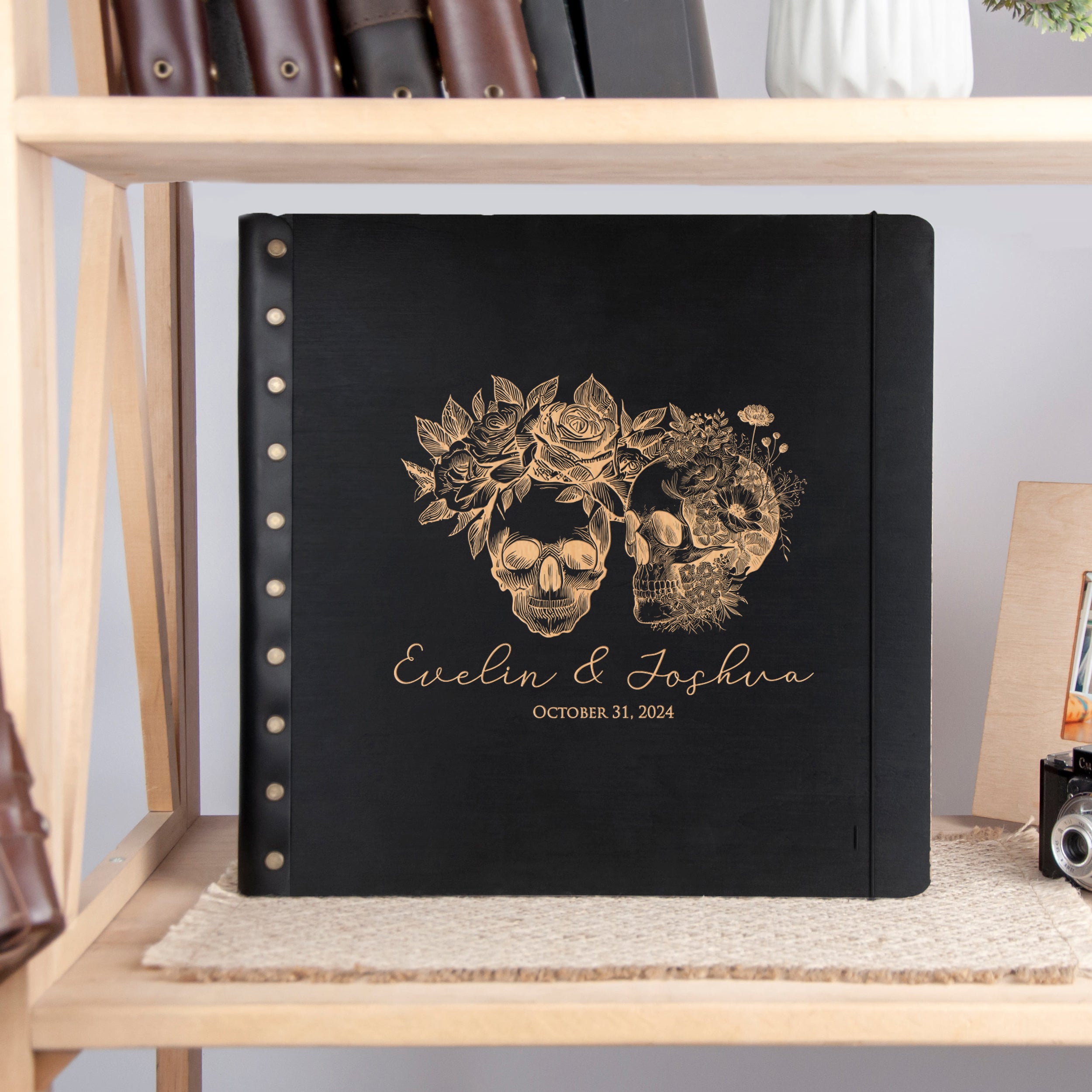 A black photo album with gold embossed skull and floral designs, featuring the names 'Evelin & Joshina' and the date 'October 31, 2014'.