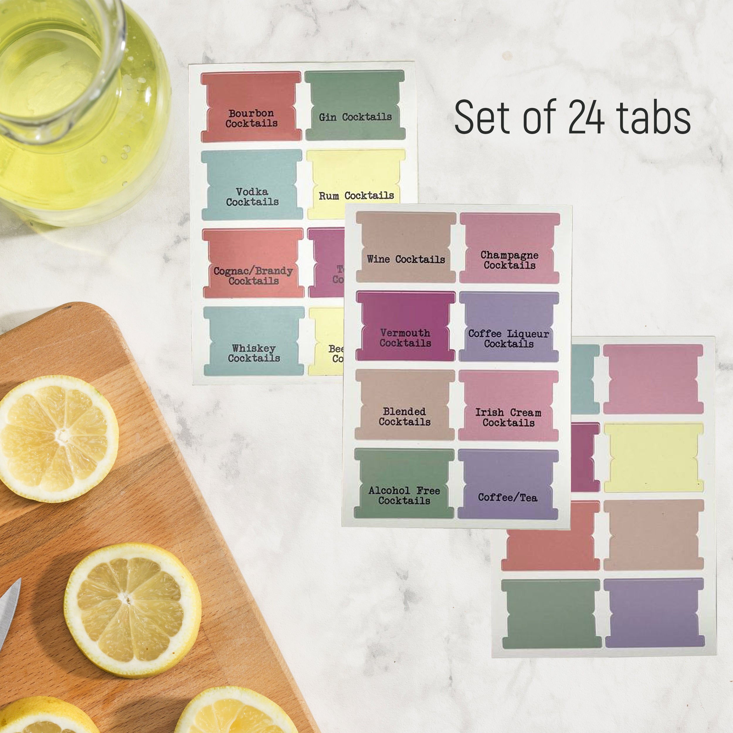 a set of 24 colorful labels for cocktails, along with a glass of lemonade and a wooden cutting board with sliced lemons.