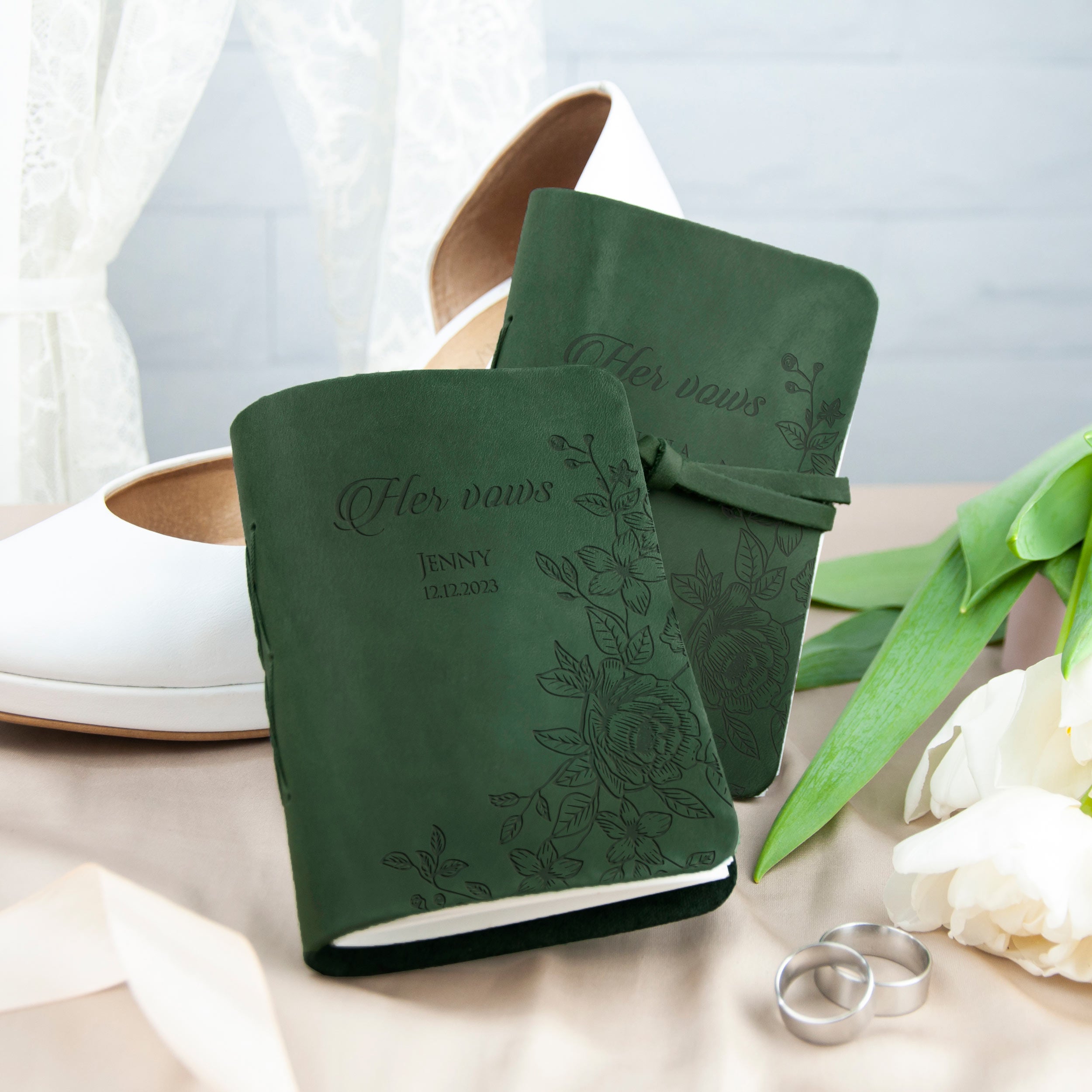 a pair of green notebooks with the text "Her vows" printed on them, along with a pair of white shoes and a bouquet of white flowers.