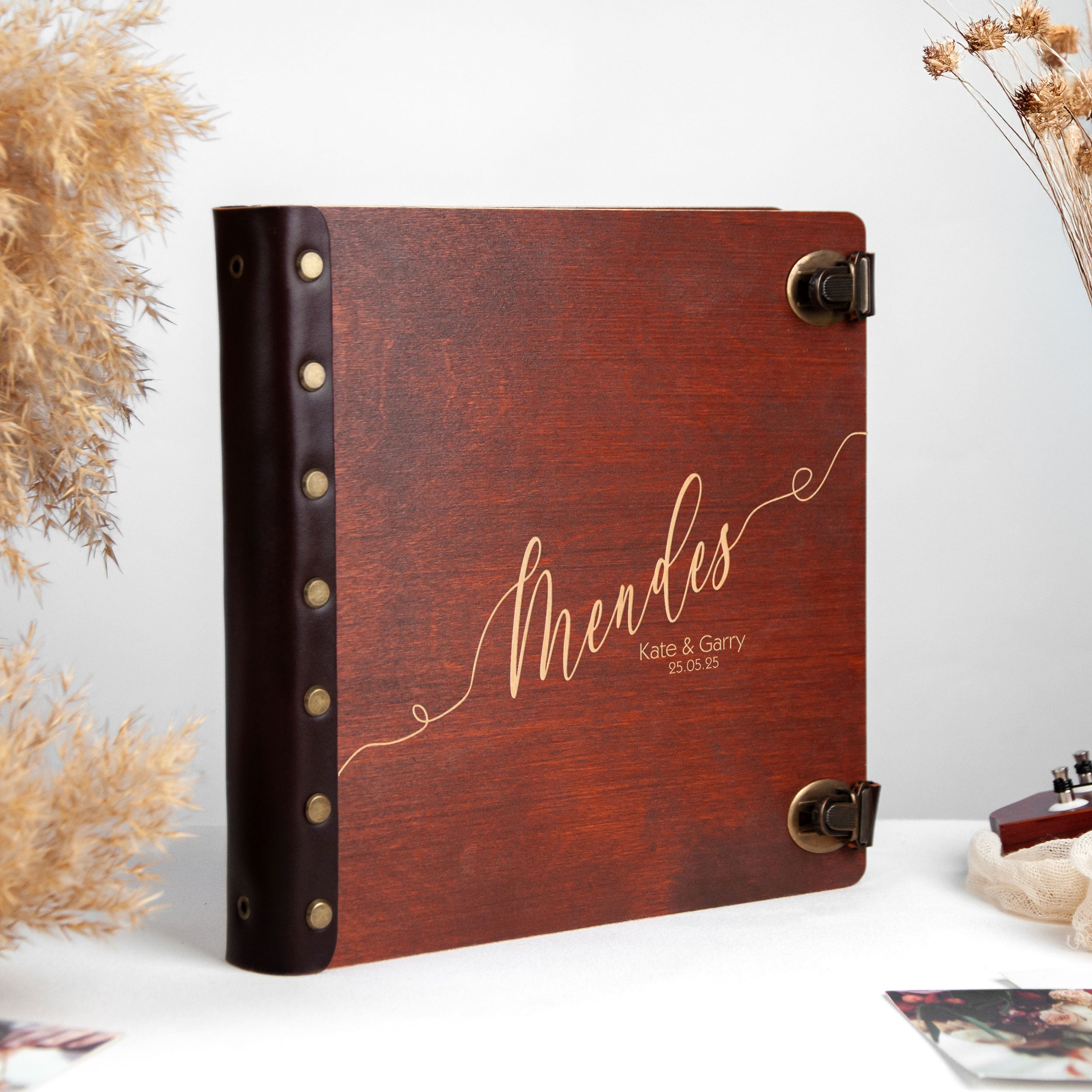 A wooden photo album with a leather cover, featuring the name 'Mendes' and the date '25.05.25' printed on it.