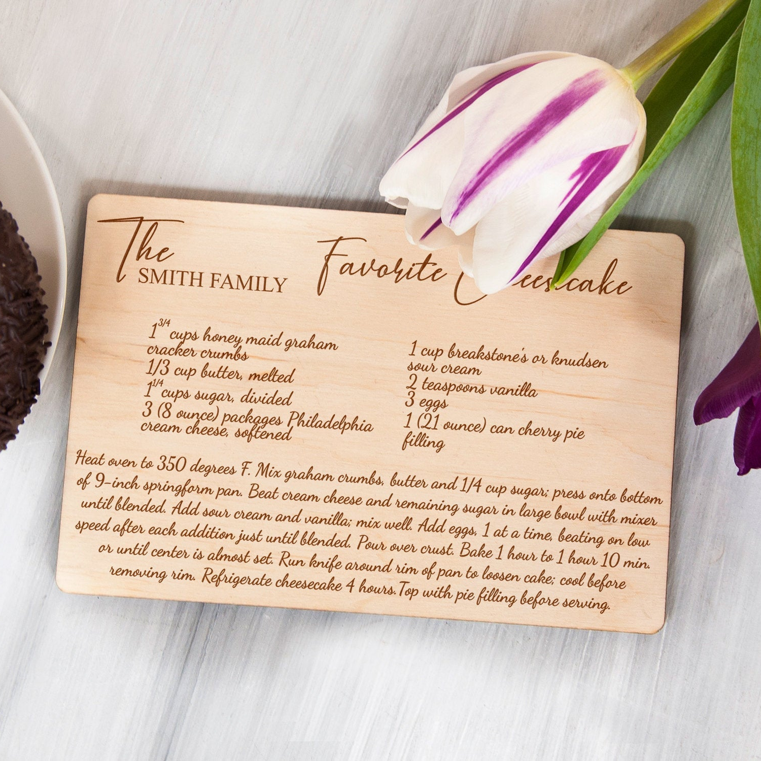 A wooden recipe card with a favorite chocolate cake recipe for The Smith Family, featuring a picture of a chocolate cake and a tulip flower.
