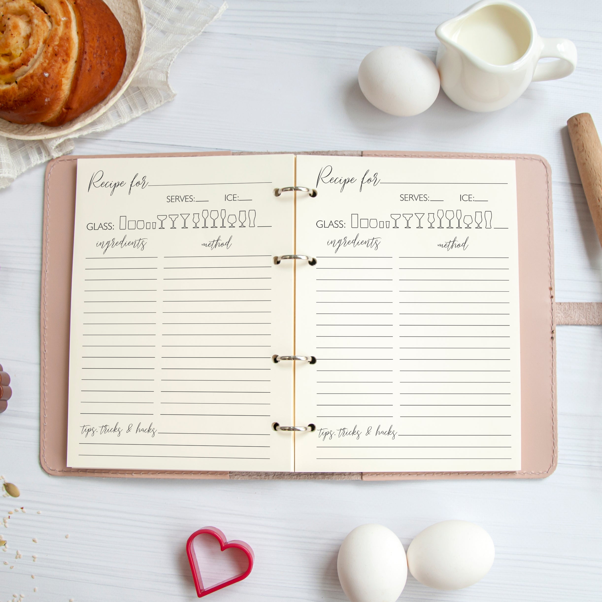 an open recipe book with a list of ingredients and instructions, along with a bowl of food and some eggs on a white surface.