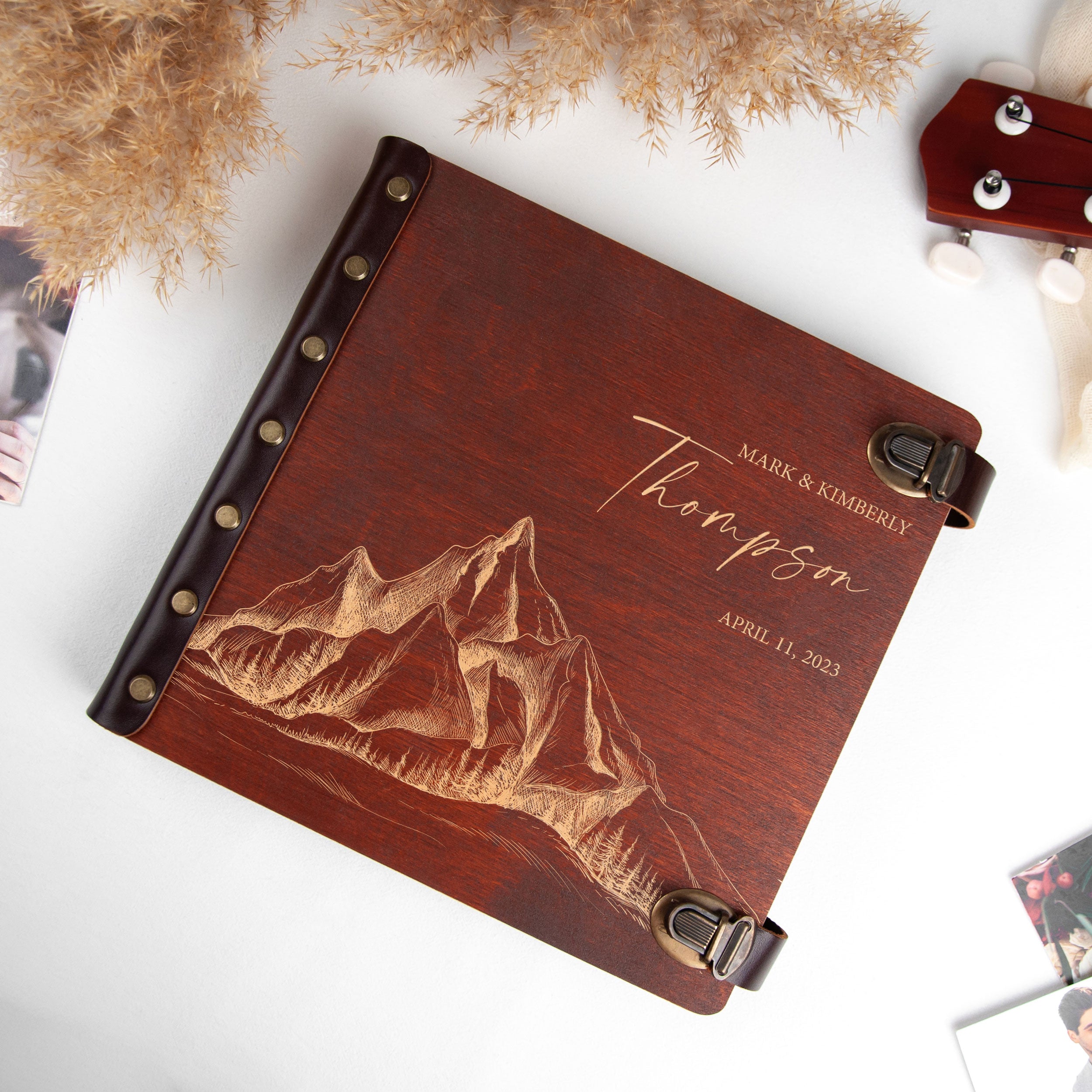 A wooden album with a mountain landscape engraved on it, placed on a white surface.