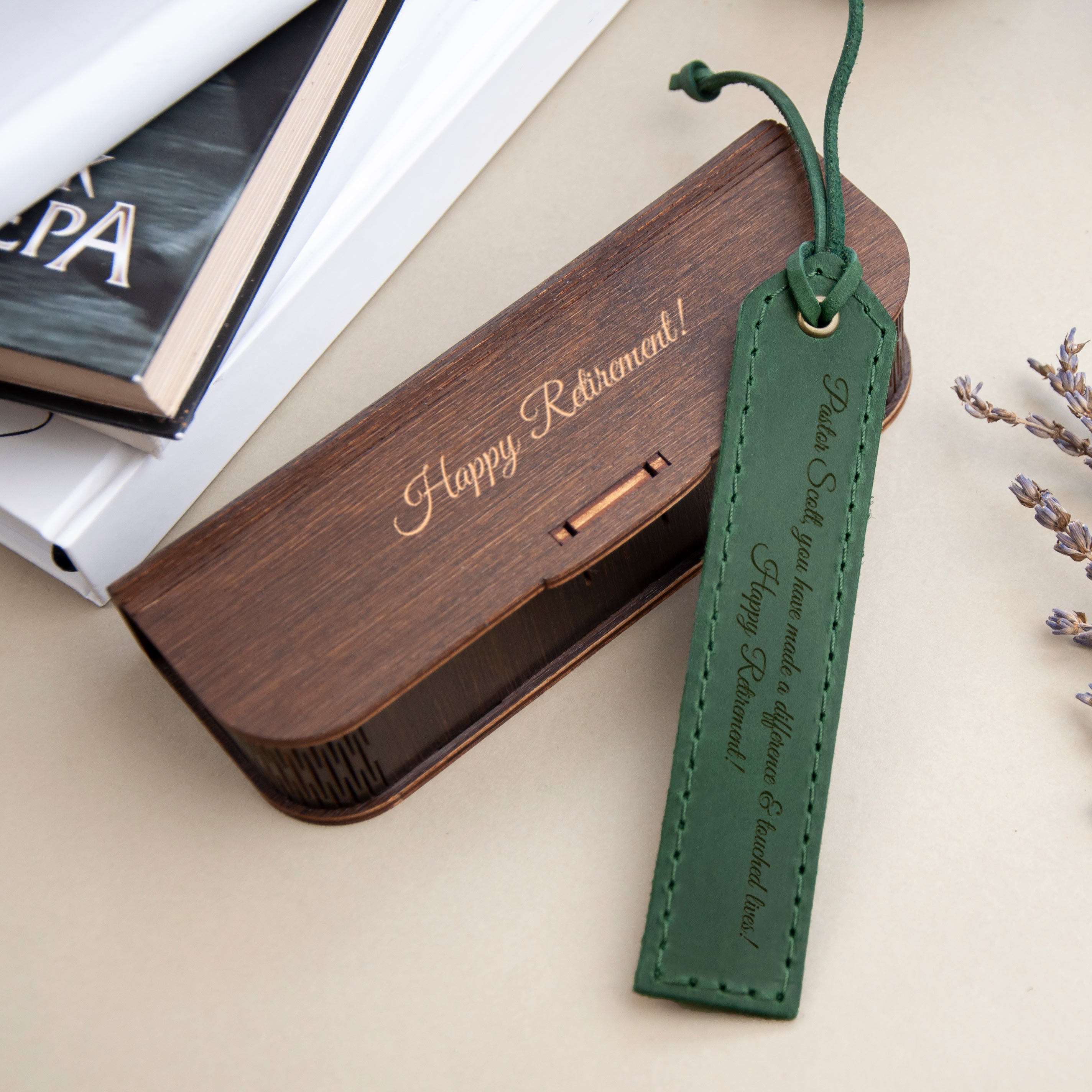 A wooden box with a personalized message engraved on it, placed on a table next to a green bookmark with a message.