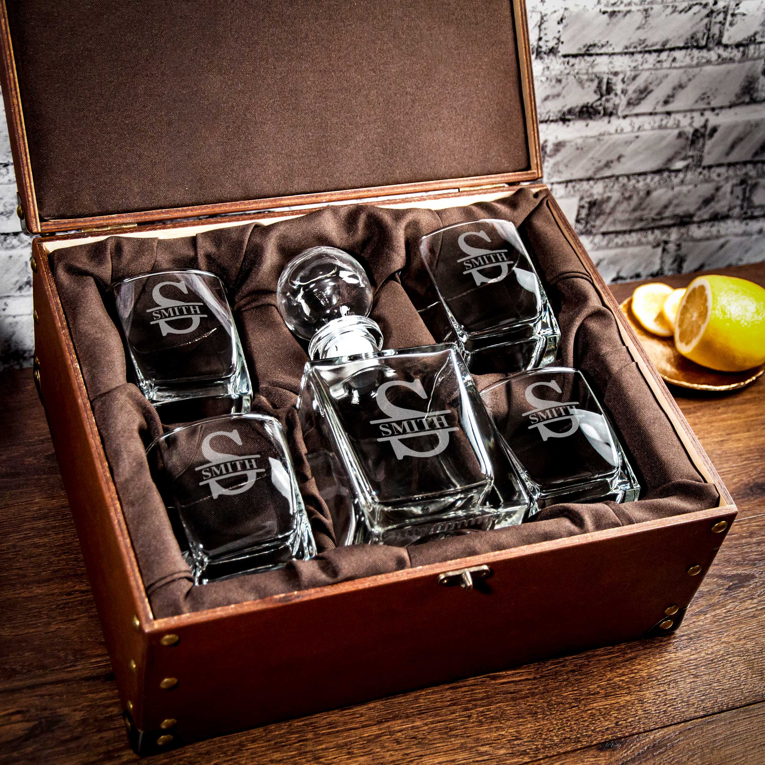 A set of six whiskey glasses with the initials "SMITH" engraved on them, placed in a brown wooden box.