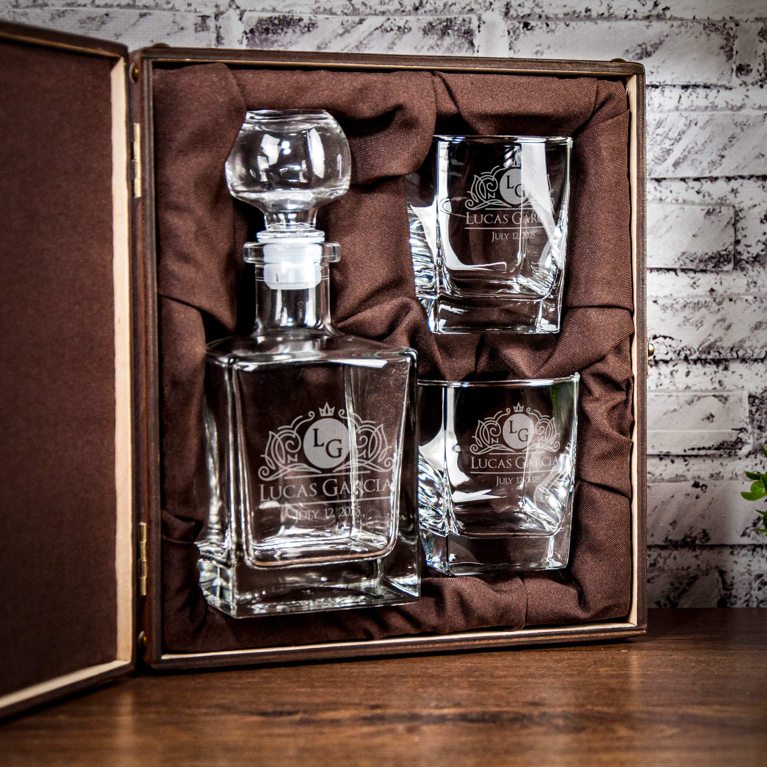 A set of three glassware pieces, including a decanter and two glasses, presented in a brown box with a velvet lining.