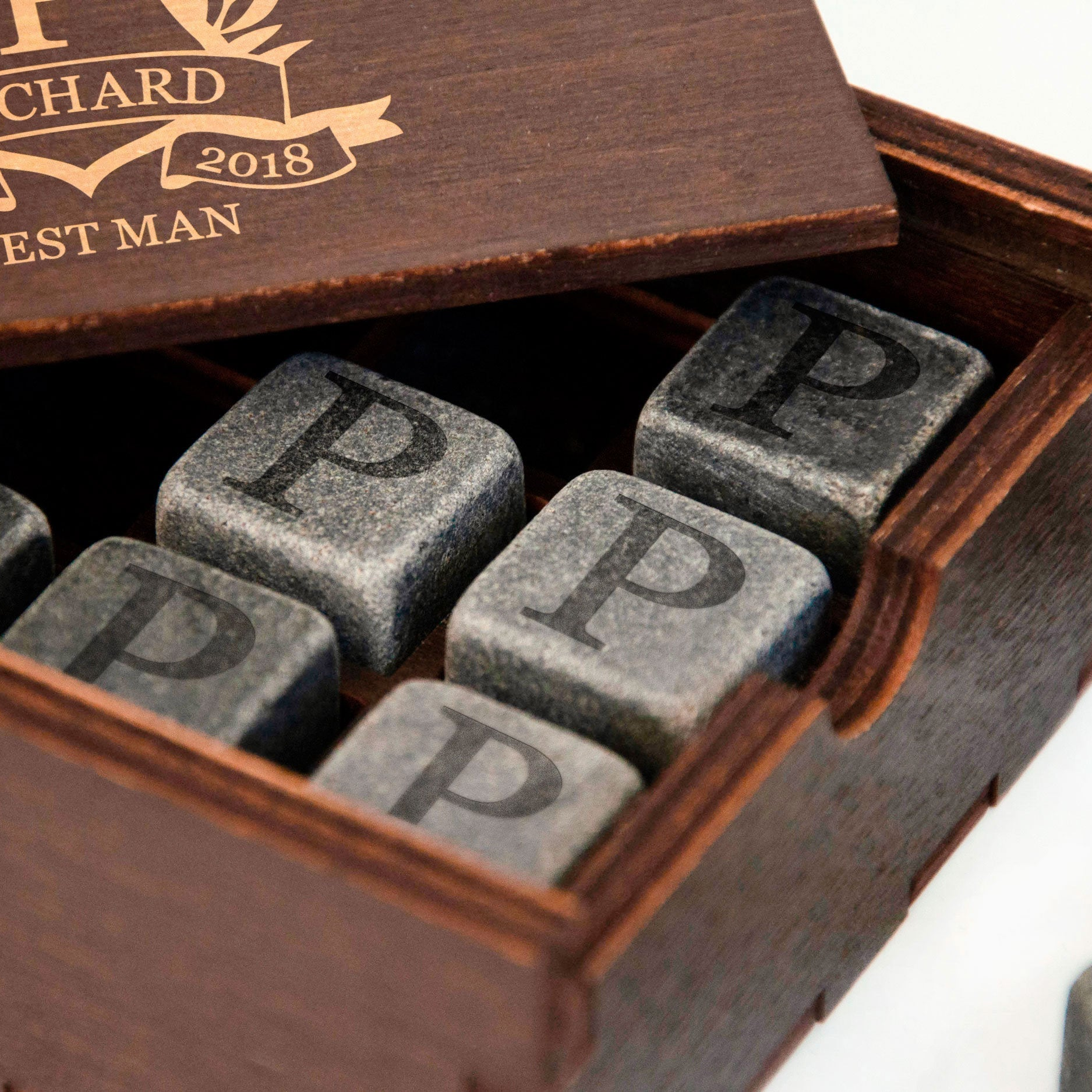 A wooden box containing several gray stone cubes with the letter "P" printed on them.