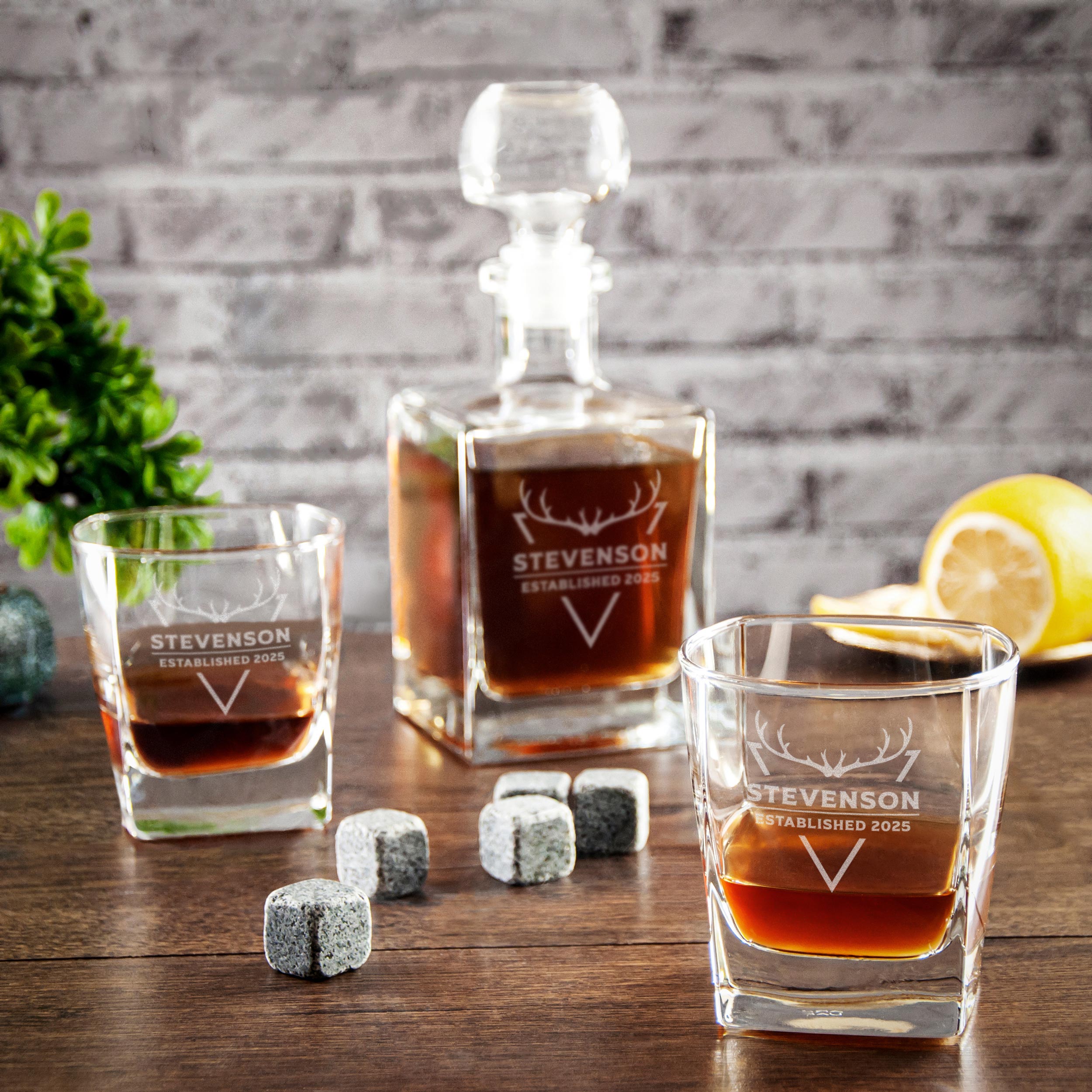 a collection of whiskey-related items, including a decanter, two glasses, and some whiskey cubes, all set against a brick wall background.