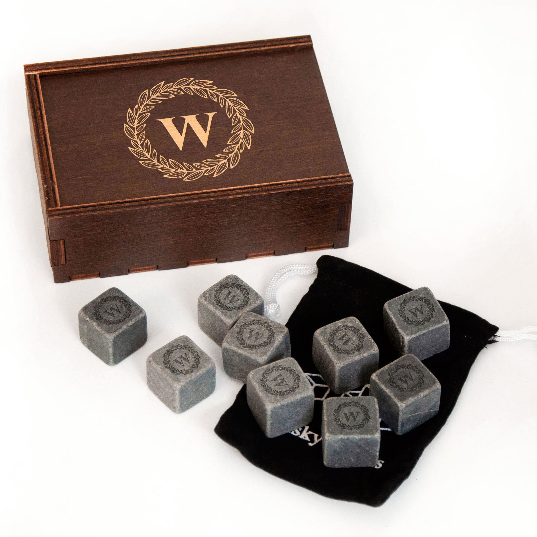 a wooden box with a gold wreath design and a black bag containing several gray stone cubes with a similar design.
