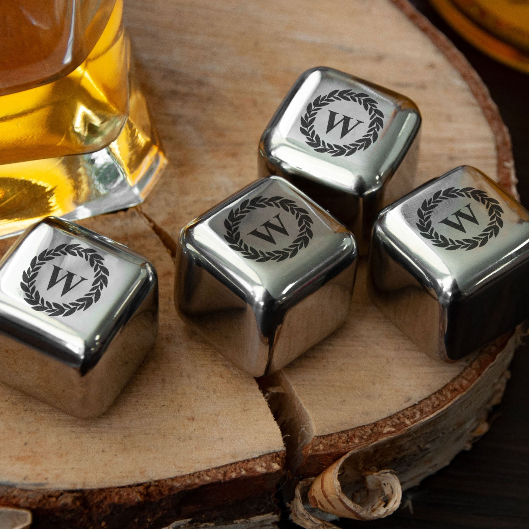 A collection of four silver cubes with the letter "W" engraved on them, placed on a wooden surface.