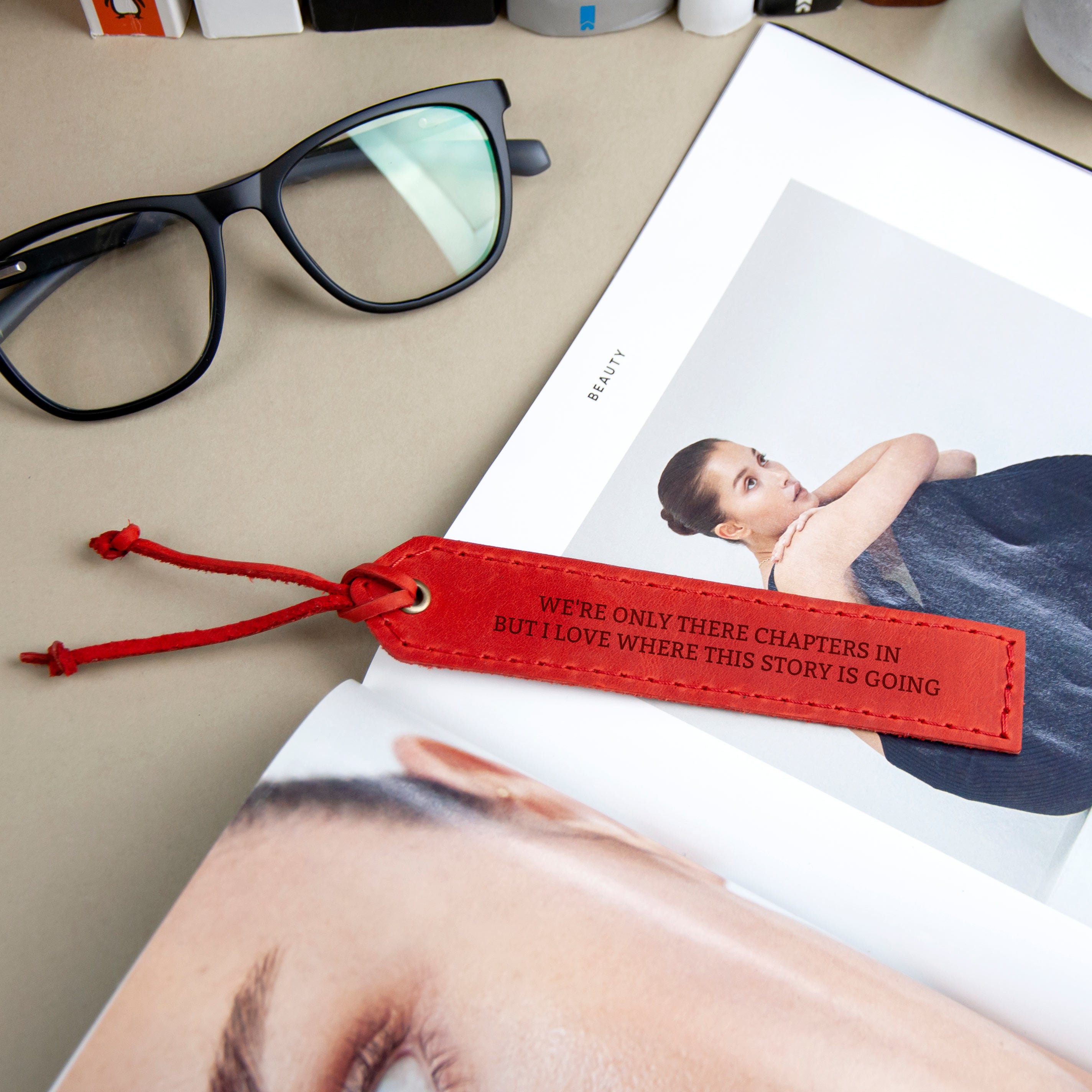 a pair of glasses, a red bookmark, and a magazine with a woman's face on the cover.